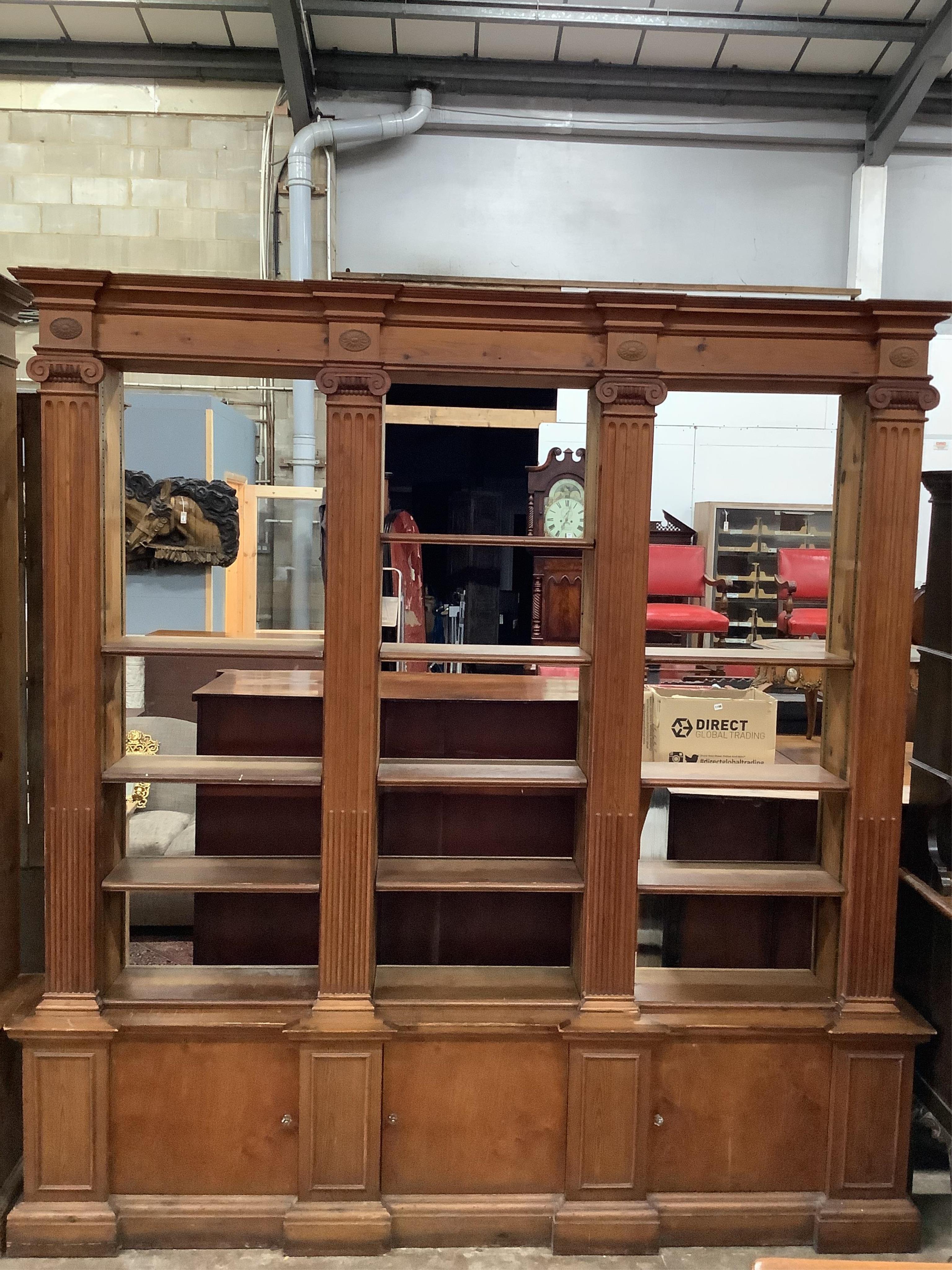 A pair of mid 20th century Sheraton style pitch pine and ply open bookcases, the adjustable shelves divided by fluted Ionic columns, each width 214cm, depth 33cm, height 222cm